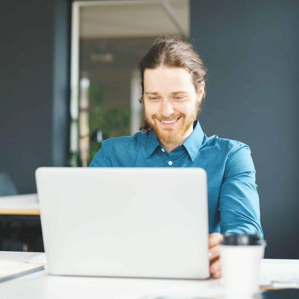 Happy young male office employee working on laptop computer