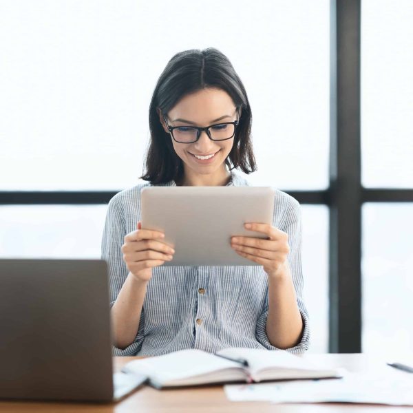 Young girl holding tablet and using laptop at office